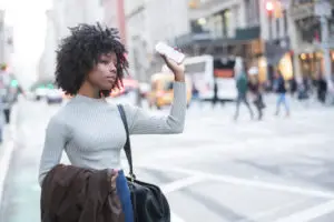 a woman holding a phone and signaling to her rideshare driver