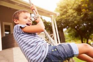 happy boy plays on rope swing