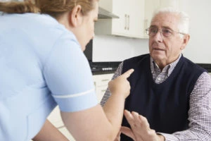 An orderly yelling at an elderly man.