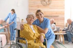 nurse hugs elderly woman in wheelchair