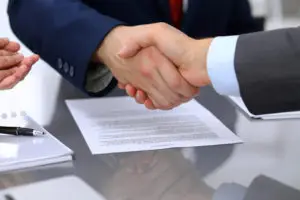 two hands shaking over contract