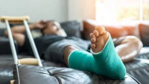 man lying on couch with foot in cast