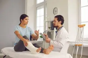 woman with leg in cast consulting with doctor