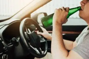 man drinking beer while driving