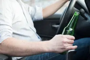 man driving with bottle of beer in hand
