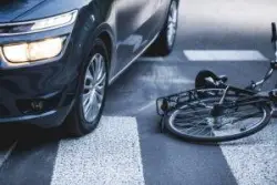 overturned bicycle next to car in crosswalk