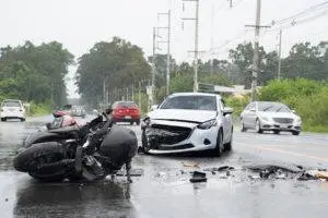 a damaged motorcycle and car in the middle of the road after a collision