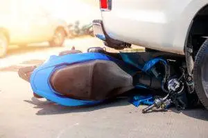 an overturned motorcycle beneath a car