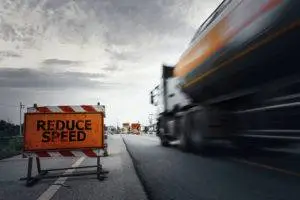 commercial truck speeding on road with reduce speed sign