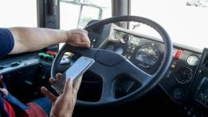 irresponsible bus driver typing on phone behind wheel