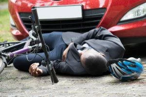 overturned bicycle and man lying in middle of road