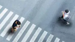 two men use phones while on crosswalk
