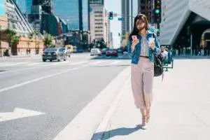 woman walks on sidewalk with phone