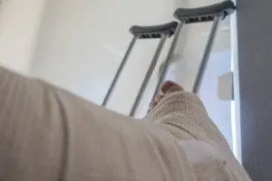 the-foot-of-a-delivery-truck-accident-victim-in-a-cast-with-crutches-against-the-wall