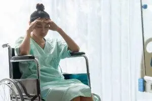 patient sitting in wheelchair holds head in reaction to discovering medical malpractice injury