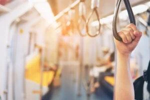 A close-up of a hand holding a handle on a public transit bus.