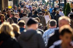 A busy crowd navigates a crosswalk without accident.