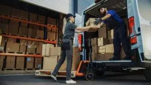 Delivery drivers loading a van at a warehouse. Amazon vehicles of any size must pay you if they cause an accident while making deliveries.