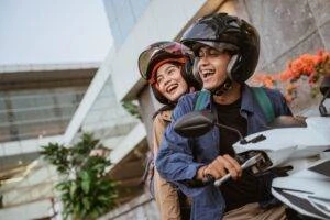 Man and woman smiling while riding motorcycle in O’Fallon.