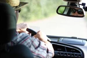 A view from the backseat of a man driving a car.