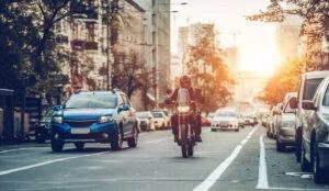 motorcycle rider drivers next to blue car on St. Charles street