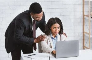 A male supervisor touches his female subordinate on the shoulders. An example of workplace sexual harassment.