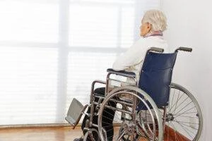 An elderly St. Peters nursing home abuse victim in a wheelchair looking out a window.