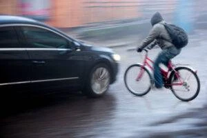 A car pulling out in front of a cyclist about to crash. If you’re ever hit by a car, contact Morelli Law for help with your accident claim.