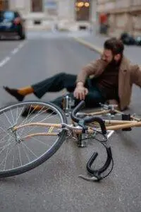 A man holding his knee in the street after a bicycle accident. He may need the help of a Marion bicycle accident lawyer.