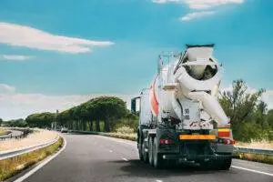 A concrete truck is in motion on the road. The high center of gravity makes concrete trucks dangerous as they are prone to rollover accidents.