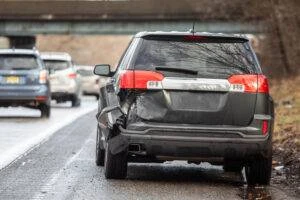 A dark gray SUV that was just in an accident sits on the side of the road while its driver wonders: Do I have to report a car accident in New Jersey?