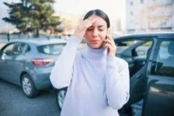 Driver standing in front of two vehicles after a crash and wondering how long after a car accident they have to file a police report in New York