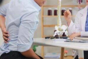 A man presses his hand against his spine after experiencing back pain. Here are the most common causes of spinal cord injuries.