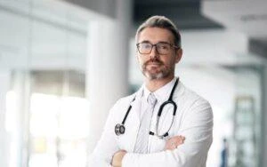 A doctor looking thoughtfully at the camera. A lawyer can explain how long you have to see a doctor after a work injury.