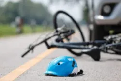 Helmet on the ground next to a bike. Call a Beverly Hills bicycle accident lawyer after an accident.