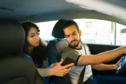 A distracted Lyft driver looking at a phone for directions. You can hire a Bakersfield Lyft accident lawyer after a collision.