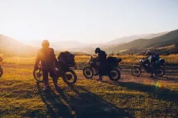 Several motorcyclists pull over to the side of the road at sunset.