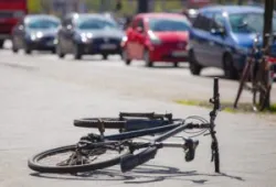 A damaged bicycle is left on the road after a collision with a car. A bicycle accident lawyer in Long Beach will help you get the maximum settlement.