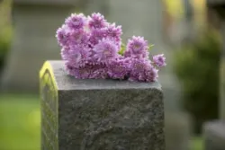 A family leaves purple flowers on top of a gravestone after a loved one’s wrongful death in Sacramento.