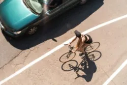 A woman rides her bike near a car. A bicycle injury attorney serving Bakersfield, CA, can help victims recover monetary damages after an accident.