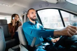An Uber driver transports a woman taking a phone call. A rideshare app accident attorney can help injured riders demand damages for an accident in Sacramento, CA.