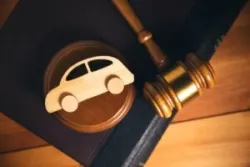 A wooden car sits on a desk near a gavel. How does the car accident lawsuit process work?