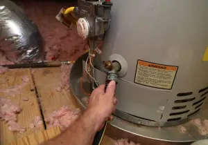 repairman attaching hose to home water heater to perform maintenance
