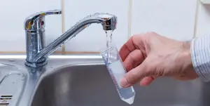 man fills test tube with sink water for testing