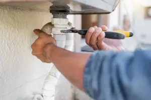 plumber using wrench on clogged pipe
