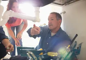 plumber showing homeowner problem with her pipes