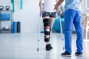 female patient walking on crutches with help