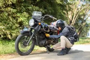 man checking his motorcycle on road