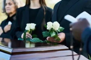 people holding white roses at a funeral