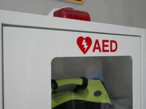 An AED hanging in a hallway. A lawyer can explain if schools can be sued for AED failures or misuse.